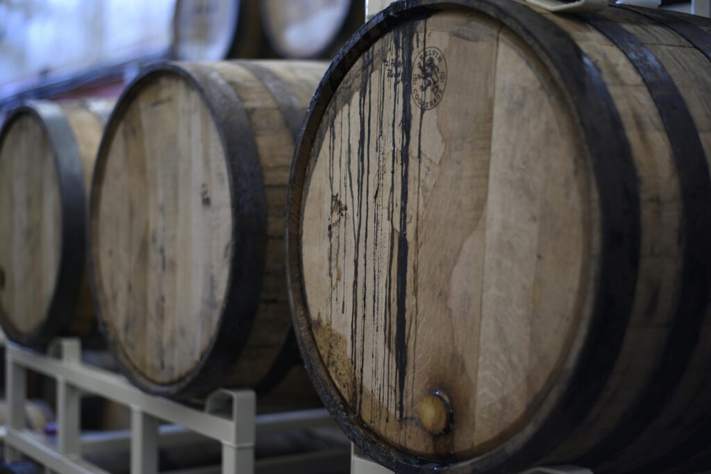 Close-up of wooden wine barrels used for fermentation and storage in a winery cellar.